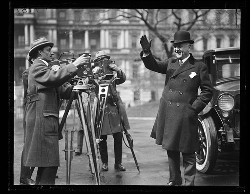 Man in front of photographers at White House; State, War and Navy Building in background. Washington, D.C.