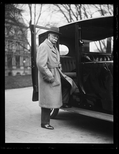 Man at automobile; State, War and Navy Building in background. Washington, D.C.