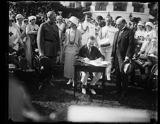 Pres. Coolidge signing the $6,800,000 Hospitalization Bill during the Garden Party, June 5, at the W.H. [i.e., White House] for disabled service men. The Bill was proposed by the Veterans Bureau