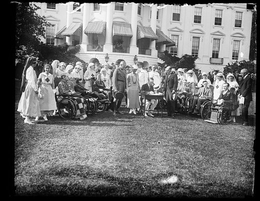 Pres. Coolidge signing the final veterans Bu. Hospital Bldg. bill at the W.H. [i.e., White House] during the garden party to the wounded soldiers. The bill provides for $6,800,000 for completing the hospital program. Center group, left to rt.: Gen. Pershing, Mrs. Coolidge, Commander Andrews, Col. C.