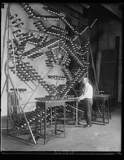 The latest in electric baseball scoreboards. George Coleman, inventor of Wash., is shown with the mechanism of the new scoreboard