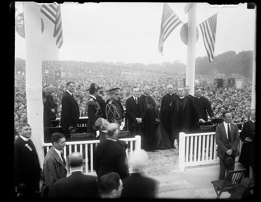 Group on stage; includes Curtis D. Wilbur, and Calvin Coolidge; with crowd and Washington Monument in background, Washington, D.C.