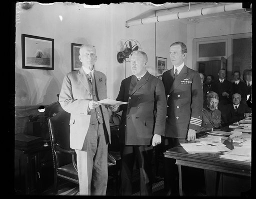 Dr. Hugh Eckener, Builder and Commander of the Z. R-3 giving his official report to Dr. Chas. D. Walcott, chmn. of the Nat'l Advisory Comm. on Aeronautics, upon his arrival in Wash., Oct. 16th. L. to r.: Dr. Walcott, Capt. Eckener, and Capt. Geo. W. Steele, who will command the big ship for the U.S.