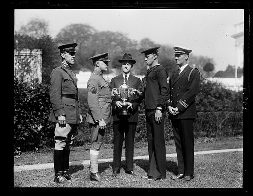 Pres. Coolidge with the cup which he had donated to be contested for annually by the enlisted men of the Army and Navy in a football contest. First game played Nov. 22, 1924. All games to be played in Wash. Left to right: Major Paul W. Baade, Army Athletic Officer; Staff Sgt. Harry O. Troupe; Pres. 