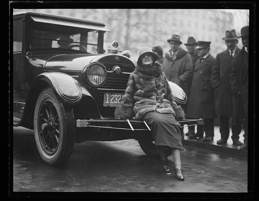 Woman seated on front of automobile