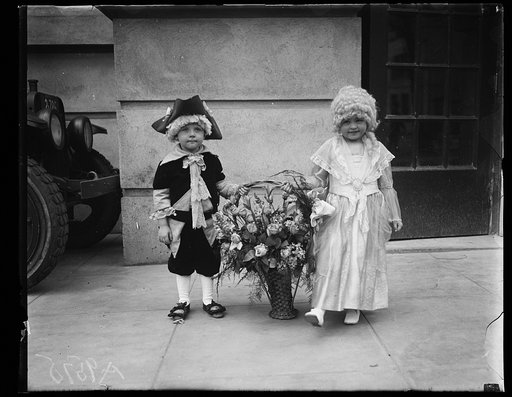 Children dressed in colonial costumes with basket of flowers