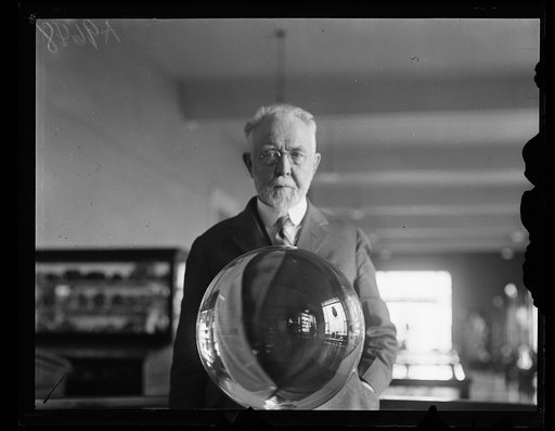 George P. Merrill, head curator of the National Museum, with the largest perfect crystal globe in the world, Washington, D.C.