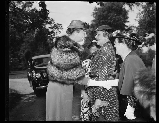 ER [i.e., Eleanor Roosevelt] shaking hands with woman in a row. Warm weather