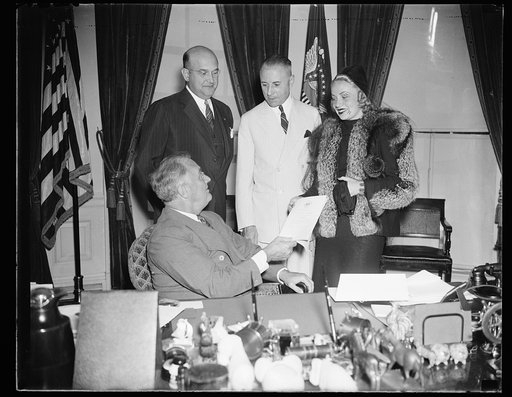 FDR [Franklin Delano Roosevelt] at desk receiving plaque from woman. 2 men