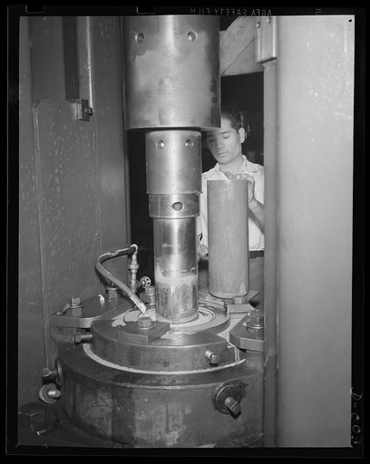 Cartridge drawing machine. Skilled worker drawing a five-inch cartridge case for the big anti-aircraft guns. The yard in which this work is performed is one of eleven Navy arsenals which are working at top speed to furnish ammunition needed for our two-ocean Navy