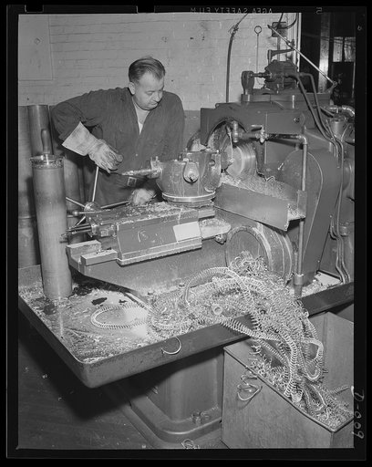Brass shavings from cartridge cases. One of the last processes in making anti-aircraft cartridges is machining the head of the case. This worker in an eastern Navy yard is one of thousands who are producing ammunition for the expanded Navy war program