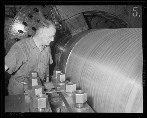 Smoothing a gun cylinder. A skilled worker in an eastern Navy yard arsenal guiding the machine which is turning a major caliber gun. He is one of thousands who are producing ammunition for the expanded Navy war program