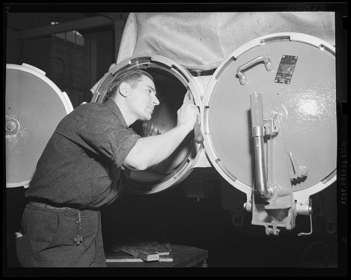 The open door to a torpedo. Close work fitting a torpedo tube door in an eastern Navy yard arsenal, one of eleven now working at top speed for the expanded war program