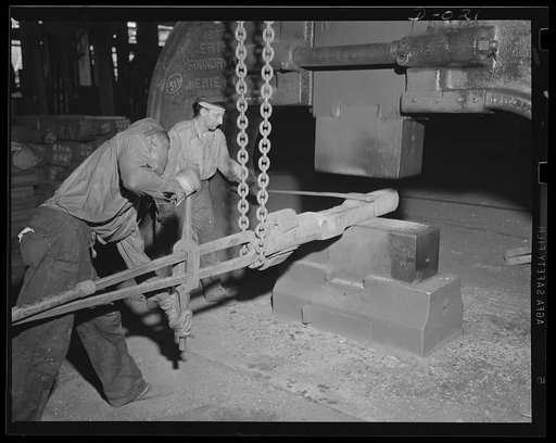 Giant tongs hold forging. Forging part of a large gun in an eastern Navy yard. This is one of eleven Navy arsenals which have stepped up production to top speed for the war program