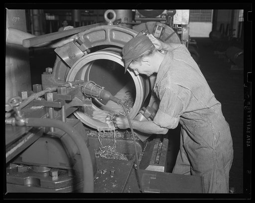 Shaving the inside of a torpedo. At work on the inside of a torpedo airflask in an eastern arsenal. The expanded two-ocean fleet will need large stores of ammunition