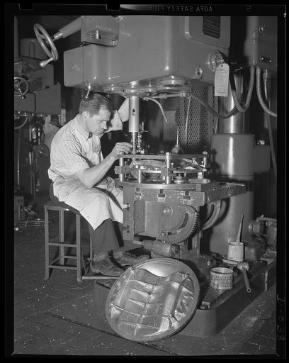 Skilled workers needed on torpedoes. Skilled drill press operator working on a torpedo bulkhead in an eastern Navy arsenal