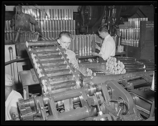 Mass production for the Army. 75 mm cartridge cases being trimmed by an accurate machine between draws. The production line is moving at top speed at a large eastern arsenal