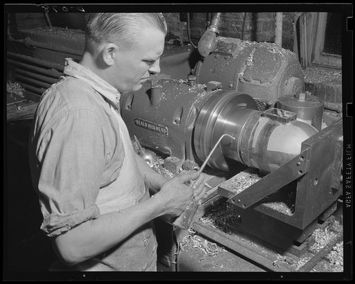 Expert machinist on armaments. Boring and facing a setter fuze in one operation at a large eastern arsenal working full speed for total war