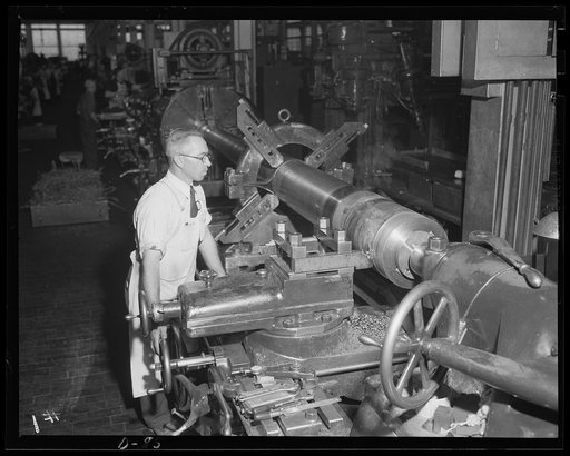 Where there's smoke... A worker in an eastern arsenal turns the thread surface on a medium-caliber gun. Note the wisp of smoke rising from the point where the thread is being cut