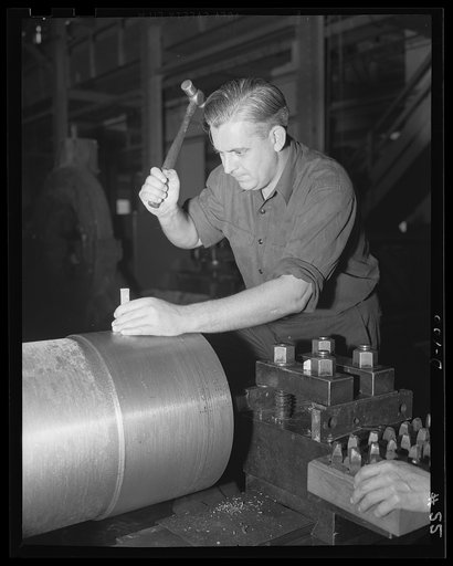 Every knock a boost. A little careful hammer work pushes a big gun along toward completion in an eastern arsenal. The man shown is stamping the location line on a medium-caliber gun