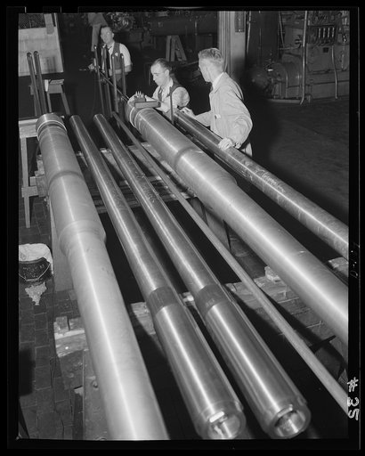 For the ramparts. A series of medium caliber guns nears completion in an eastern arsenal. Men shown are engaged in the exterior inspection of liners on guns for the war production program