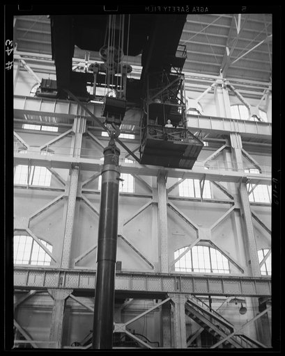 Going down! Partially-assembled, a big gun is lowered into the shrinkage pit of an eastern arsenal, where the cannon is nearing completion for the war program