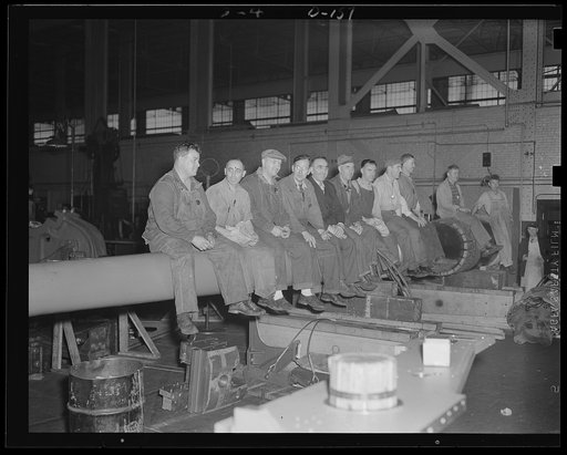 Momentary lull. Workmen rest on an 8-inch gun barrel during lunch hour. This group is part of many men working at top speed on war orders at an eastern arsenal