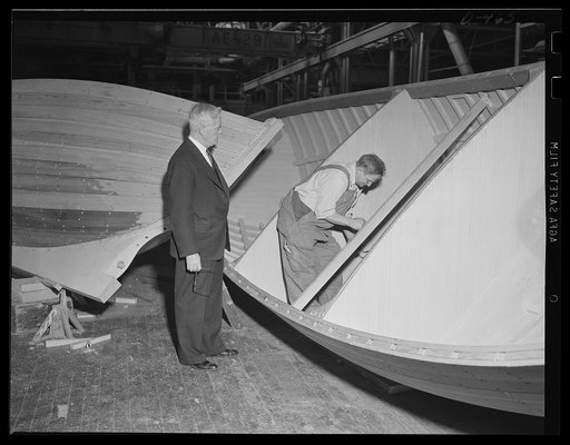 Close harmony. The workman's hand and eye are coordinated in the building of a 26-foot whaleboat at an eastern Navy yard. The shopmaster looks on