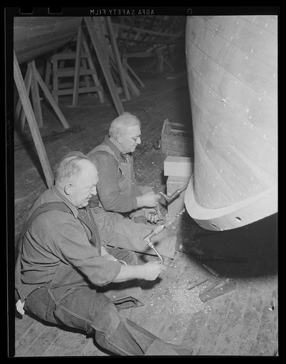 Not as easy as it looks. The men may be seated, but drilling boat holes in the keel of a Navy motor-launch is no child's play. The boat is under construction in the shipwright shop at eastern Navy yard