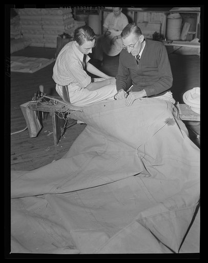 It takes the palm. A sailmaker wields palm and needle in the sail loft at an eastern Navy yard, as an apprentice looks on. The canvas is being prepared as a deck awning for one of Uncle Sam's warcraft