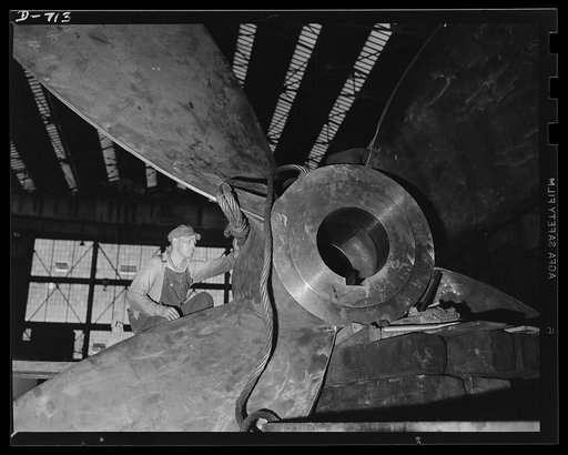 Newport News, Virginia. Worker attaching wire cable preparatory to lifting a cast propellor for a C-3. Formerly propeller blades were bolted on to the shaft, but today the propeller is cast in one piece