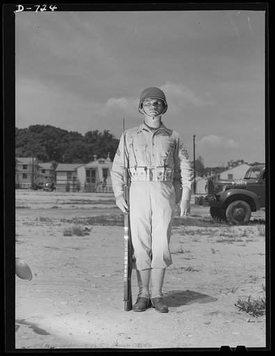 New Army helmet. Corporal French L. Vineyard, Company M, 12th Infantry, wearing a new Army helmet. Corporal Vineyard is wearing the combat pack and cartridge belt and is equipped with a Garand rifle with bayonet affixed