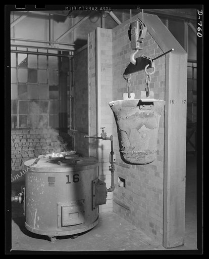 Magnesium is used to make light, strong casting for airplane engines. As insurance against possible shortages of this vital metal, Ford has built its own magnesium foundry. The pot in this photo has just been removed from one of the furnace. This pot holds 100 pounds of the magnesium alloy, which is