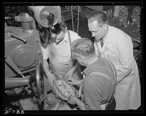 Students machinists being shown the proper finish required on gear pockets and bearing shaft bores of an aluminum oil pump housing. Packard marine plant