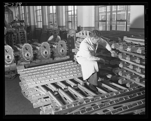 In the stockroom of the Packard marine engine plant, Detroit, Michigan. Aluminum side rails in the foreground. In background are finished crankcases with studs assembled