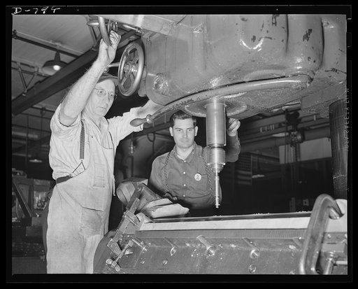 Workmen counter-boring stud holes for the cylinder barrel in an aluminum crank-case for the Packard marine engine. Packard marine engine plant, Detroit