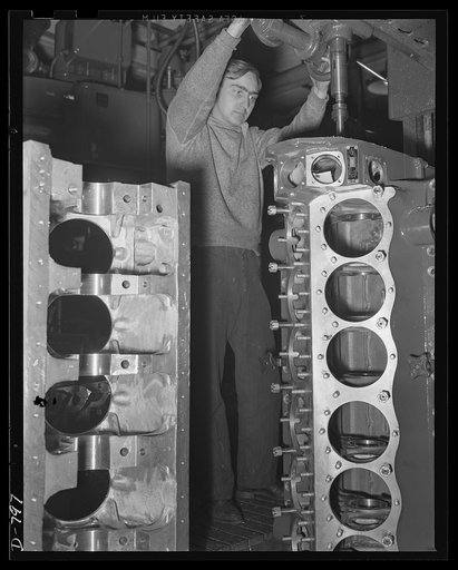 Machinist drilling stud holes in the super-charger end of the upper half of an aluminum crankcase. The crankcase is for the Packard marine engine. Packard marine engine plant, Detroit