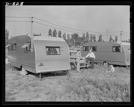 Defense housing, Erie, Pennsylvania. B.J. Rogan (right), defense worker at the General Electric plant in Erie, Pennsylvania, chats with a neighbor while his young son, Bernie, plays on the 25 x 50 foot plot of ground provided for each trailer. Notice the electric power lines which provide each trail
