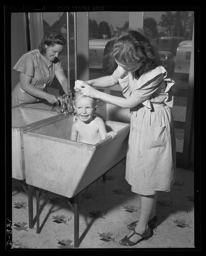 Defense housing, Erie, Pennsylvania. Mrs. Rogan bathes her young son, Bernie, in the laundry tub of the utility building. Many mothers at the site seem to prefer this for thier children to the showers provided for bathing. Wash basins and toliet facilities are also provided