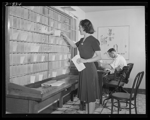 Defense housing, Erie, Pennsylvania. Interior of administration building at trailer site. Milton Ackerman (right), project manager, reviews applications of prospective trailer residents while an assistant sorts mail for trailer tenants