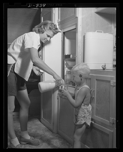 Defense housing, Erie, Pennsylvania. Mrs. Henry Colomy Jr., pours fresh, cold milk for her young son. Each defense trailer is equipped with an insulated ice-box. Other equipment includes a gasoline pressure stove and heater drop-leaf table, wash basin, and two convertible beds