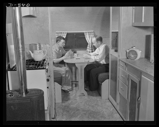 Defense housing, Erie, Pennsylvania. B.J. Rogan and a fellow worker enjoy a quiet evening of cards in his defense trailer home. The seats pull out, pullman fashion, to form a bed by night. Notice the gasoline pressure stove and heater at left