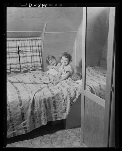 Defense housing, Erie, Pennsylvania. Two of the defense trailer youngsters are tucked in for the night. Their pullman-like bed folds into two seats by day, forming a dining alcove, along with a drop-leaf table. Notice the privacy made possible by two doors, which have dressing mirrors on the opposit