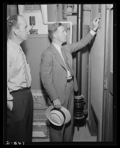 Defense housing, Erie, Pennsylvania. J.P. Kane, defense housing project manager at the Franklin Terrace project, explains the forced-air heating system of a defense home to B.J. Rogan, worker in the General Electric plant at Erie, Pennsylvania