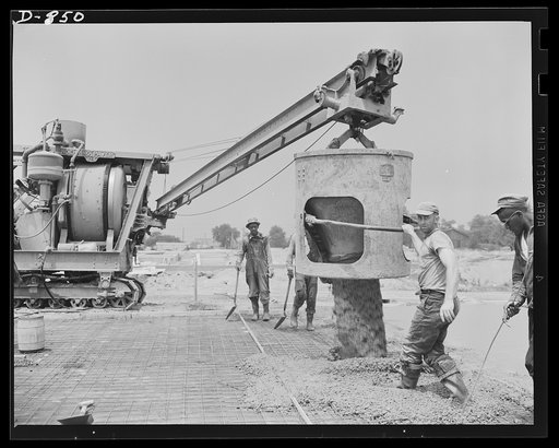 Defense housing, Erie, Pennsylvania. Concrete flooring is poured over the wire reinenforcements. The large container shuttles from the mixer to the desired location, supported by a movable crane. Three men, aided by a crew of levelers, can lay a floor of four-unit building in a few hours