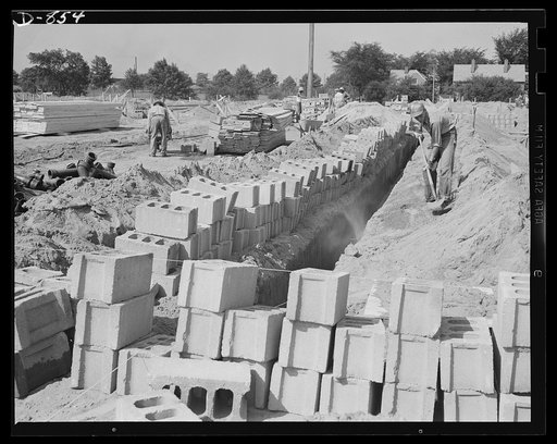 Defense housing, Erie, Pennsylvania. Cement foundation blocks ready to be mortared in place in the five-foot foundation ditch. This depth affords protection against frost which is particularly heavy in this area. Since, for reasons of economy, no basement is provided, cinder is used to fill in to fl