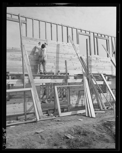 Defense housing, Erie, Pennsylvania. The wall sheeting mounts rapidly. Pre-cut sheeting is always at hand to keep this carpenter supplied, thereby cutting down waste time