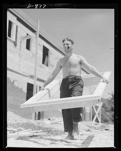 Defense housing, Erie, Pennsylvania. Window and door frames are pre-fabricated at the site by specialized crews. They are given a primer coating of paint before being assembled into the structure. One of these pre-fabricated window frames is shown here being carried to the point of installation