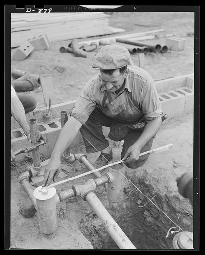 Defense housing, Erie, Pennsylvania. Plumbing that has been assembled at a central shop on the construction site is speedily placed in the foundation of a defense house at the Franklin Terrace housing project