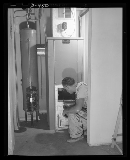 Defense housing, Erie, Pennsylvania. A workman installs a forced-air heating system in one of the 300 defense homes located at the Franklin Terrace housing project. This unit burns coal